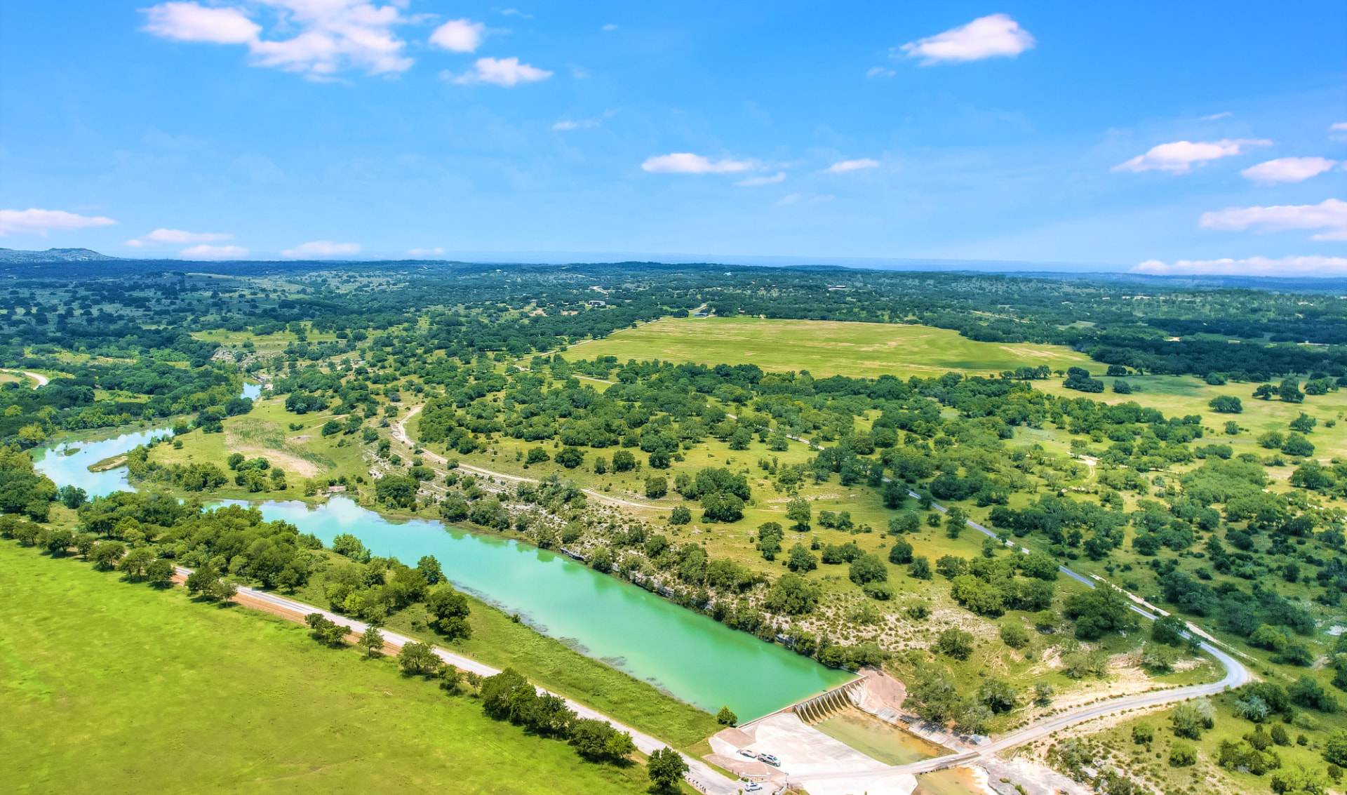 Aerial view of green Texas Hill Country land and a winding river
